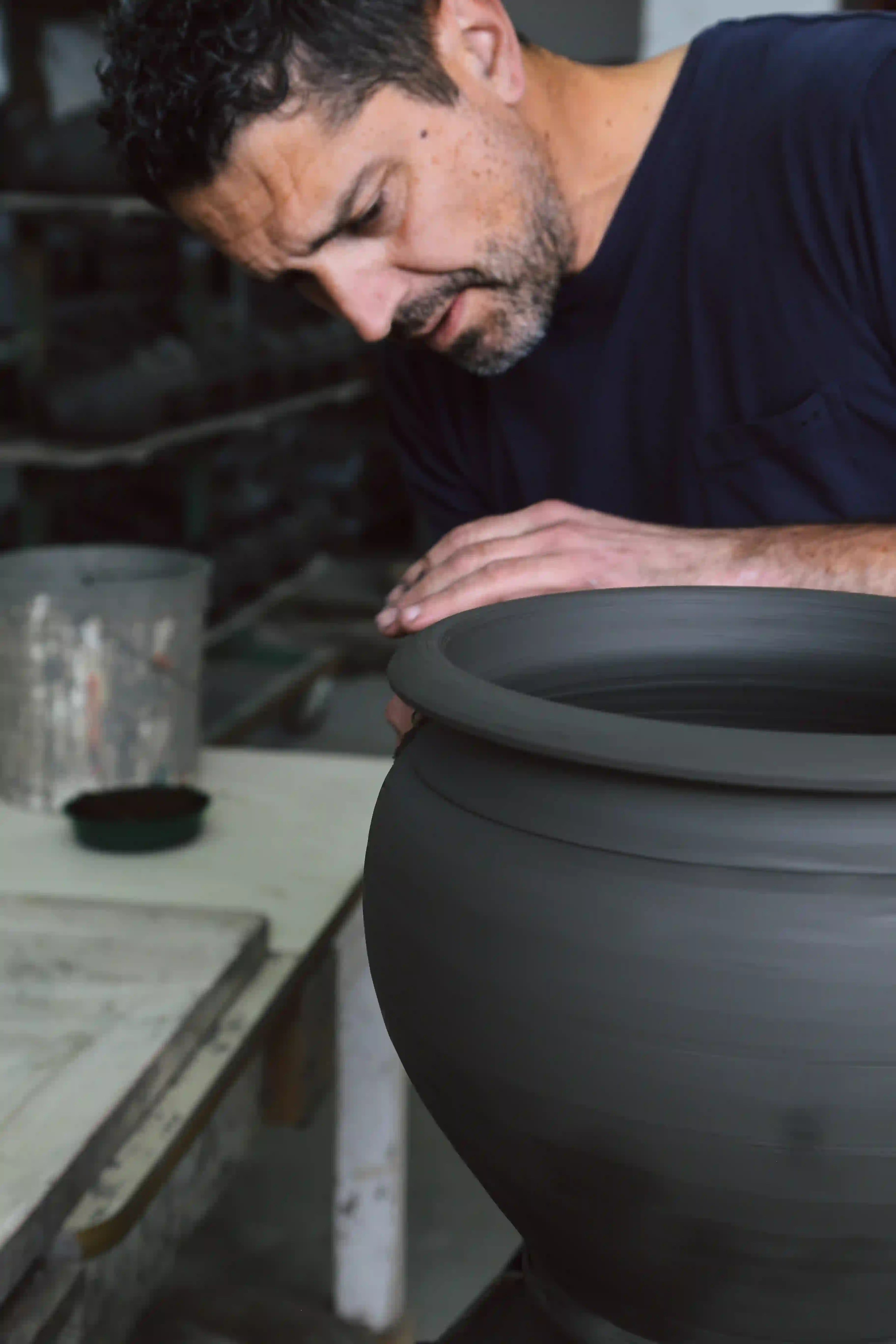 Man working on a large black pot in a workshop setting