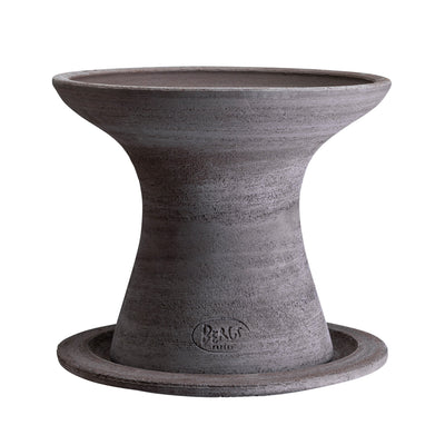 Concrete-finished Bergs Potter planter sitting on matching saucer with a textured surface on a white background
