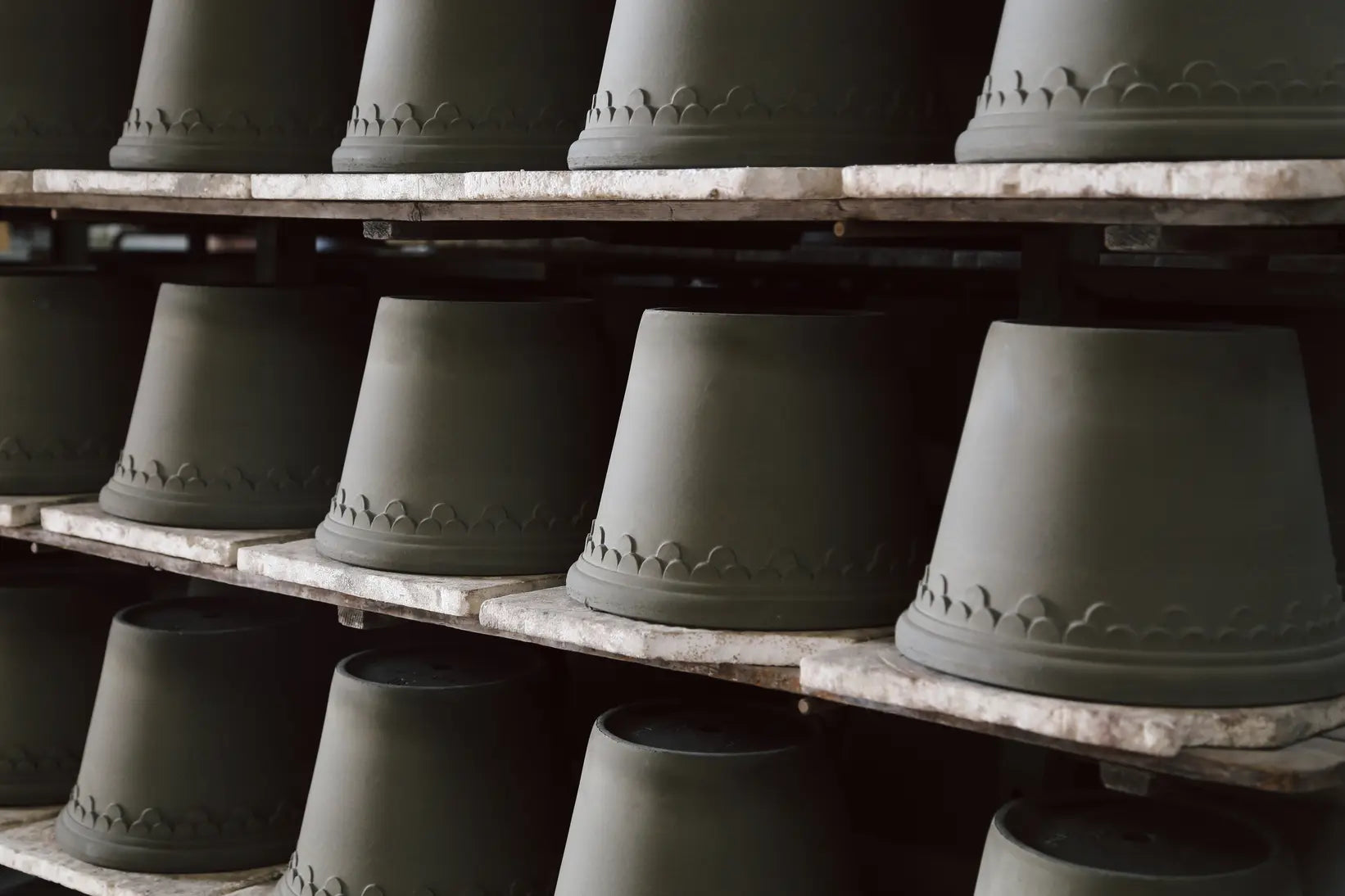 Row of raw clay ceramic pots on a wooden shelf