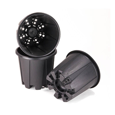 Several black plastic planter pots lie in different positions on a white background