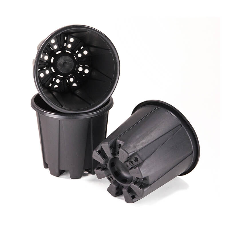 Several black plastic planter pots lie in different positions on a white background