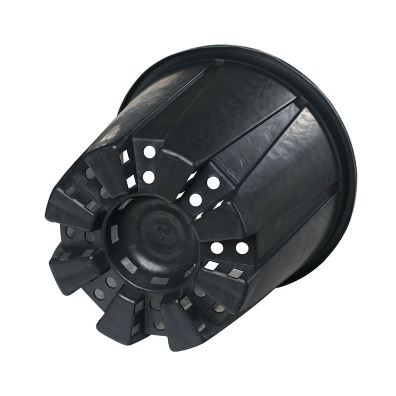 Black plastic pot lies on its side showing base with drainage holes.